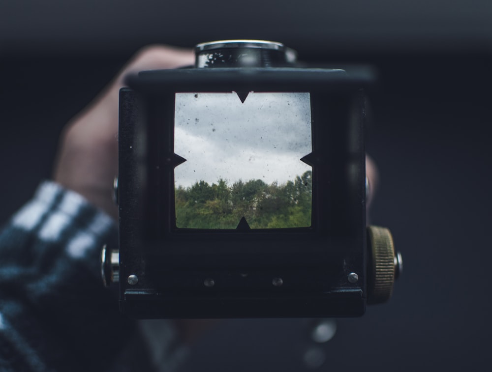 Schwarze Kamera fotografiert tagsüber grüne Bäume