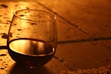 A glass of deep red wine resting on a sunlit stone wall.