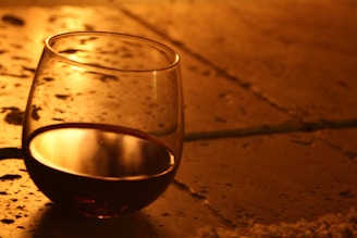 A glass of red wine catching the golden hour light on a rustic wooden table at Le Volpi.