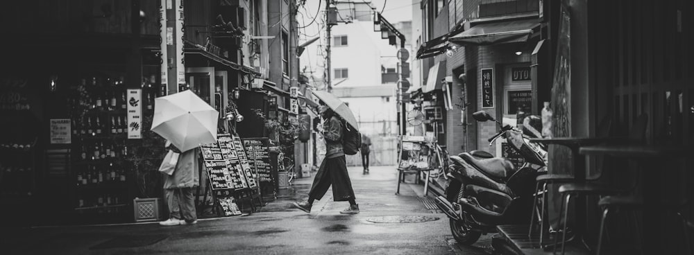 grayscale photo of man in black coat walking on street