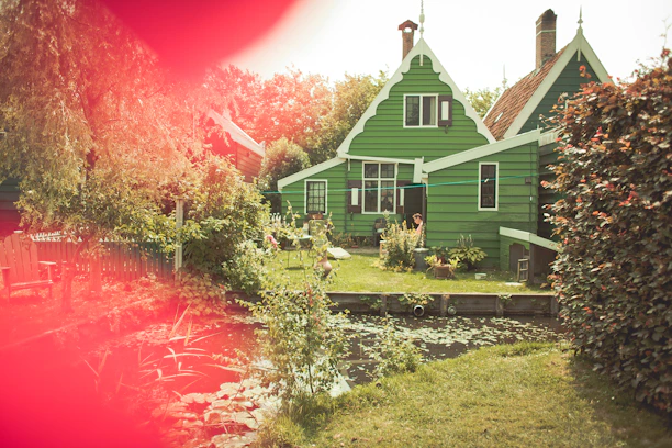 Charming country house with wooden deck and flowering garden in warm sunlight