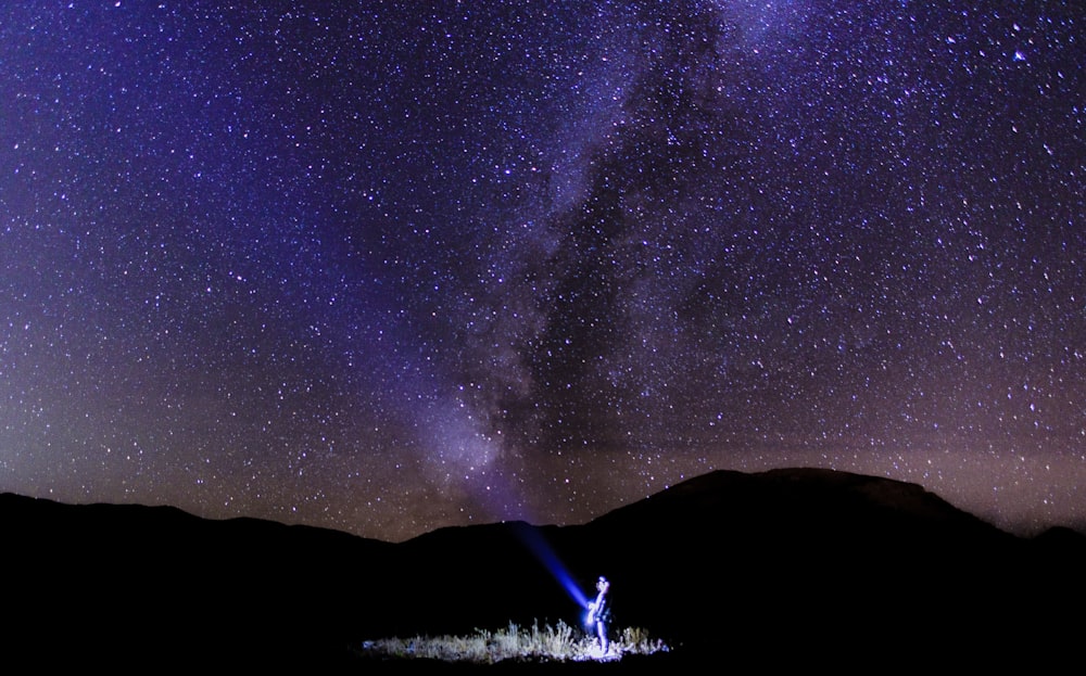 person holding light in milky way