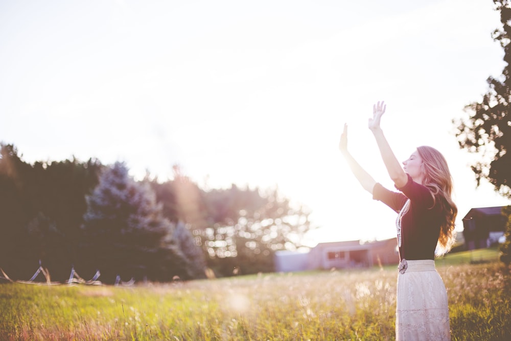 woman hands up in front of green meadows