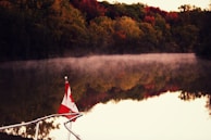 A serene morning view of a misty lake surrounded by autumn trees in Canada.
