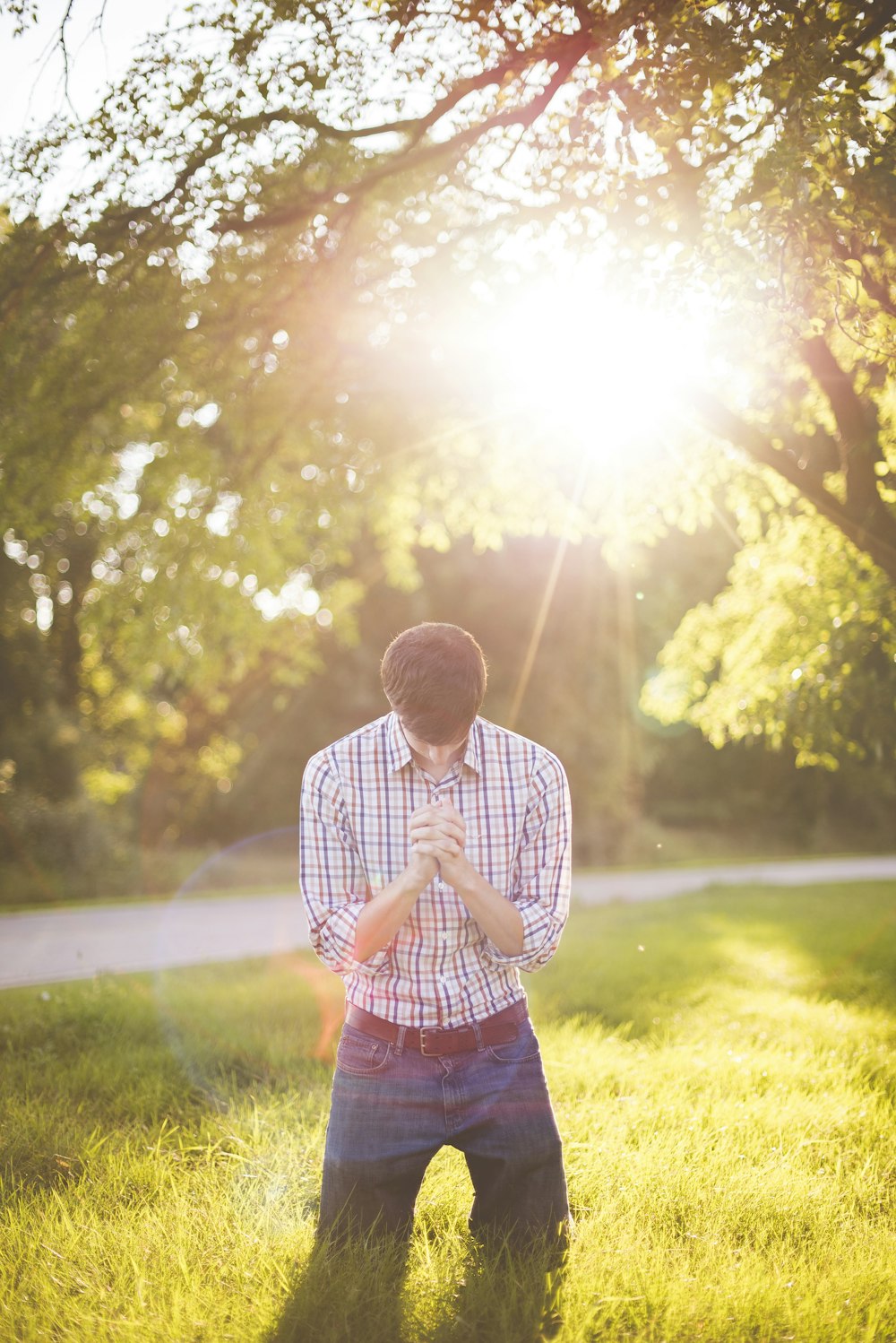 photo of man kneeling on grass near tree