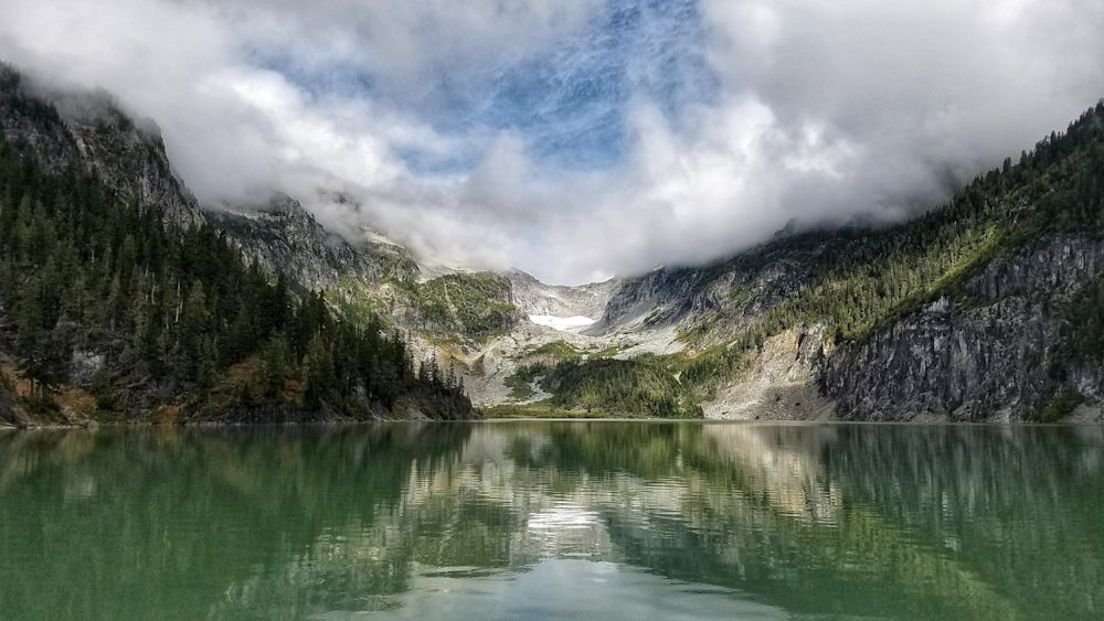 Landschaftsfotografie von Bergen, umgeben von Kiefern und Gewässern