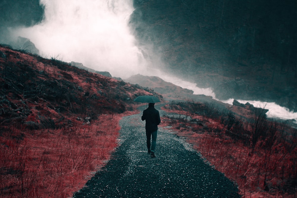 painting of man walking down a road holding umbrella