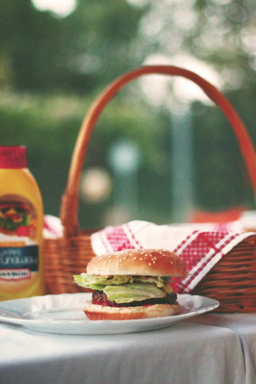 Hamburger auf Keramikteller neben Picknickkorb