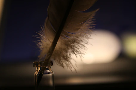 Close-up of white feather centerpiece softly lit by flickering candles on a polished table.