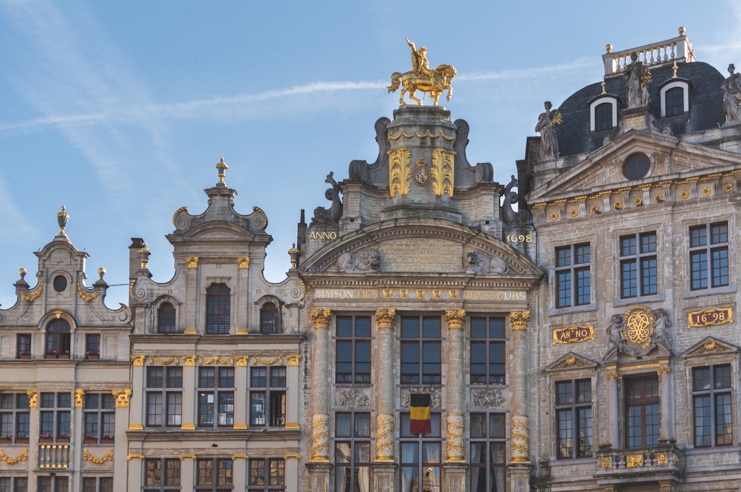 Brussels - The intricate gold-trimmed guildhalls of the Grand Place in Brussels under a clear summer sky.