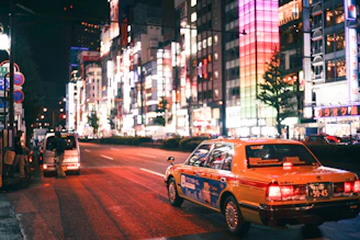 A taxi cruising through a vibrant city street with landmarks in the background.