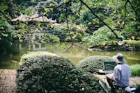 man painting front of river with temple at daytime