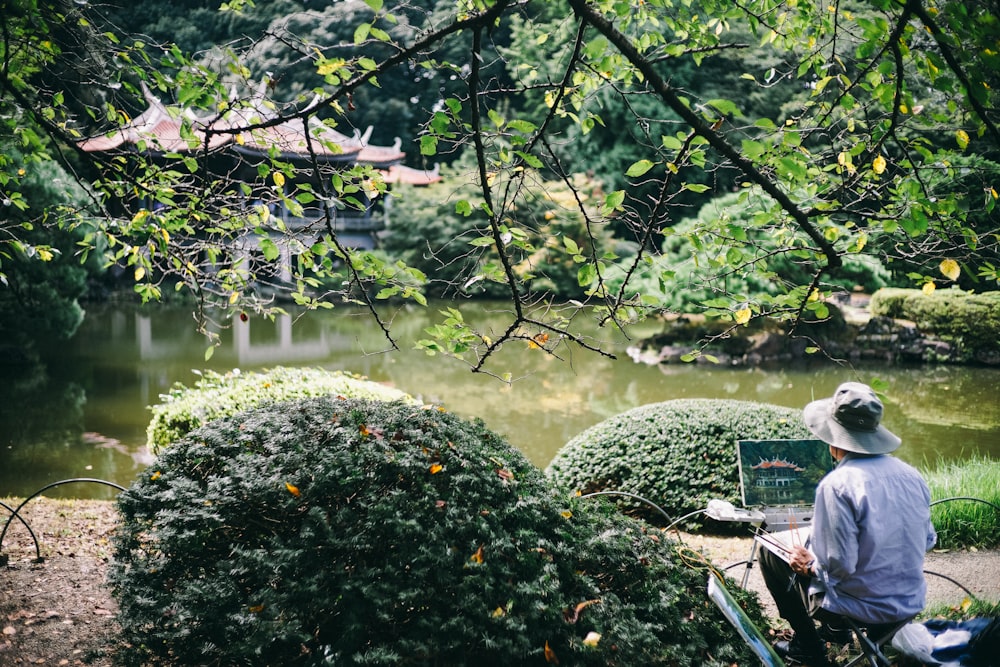 昼間、寺院のある川の前を描く男