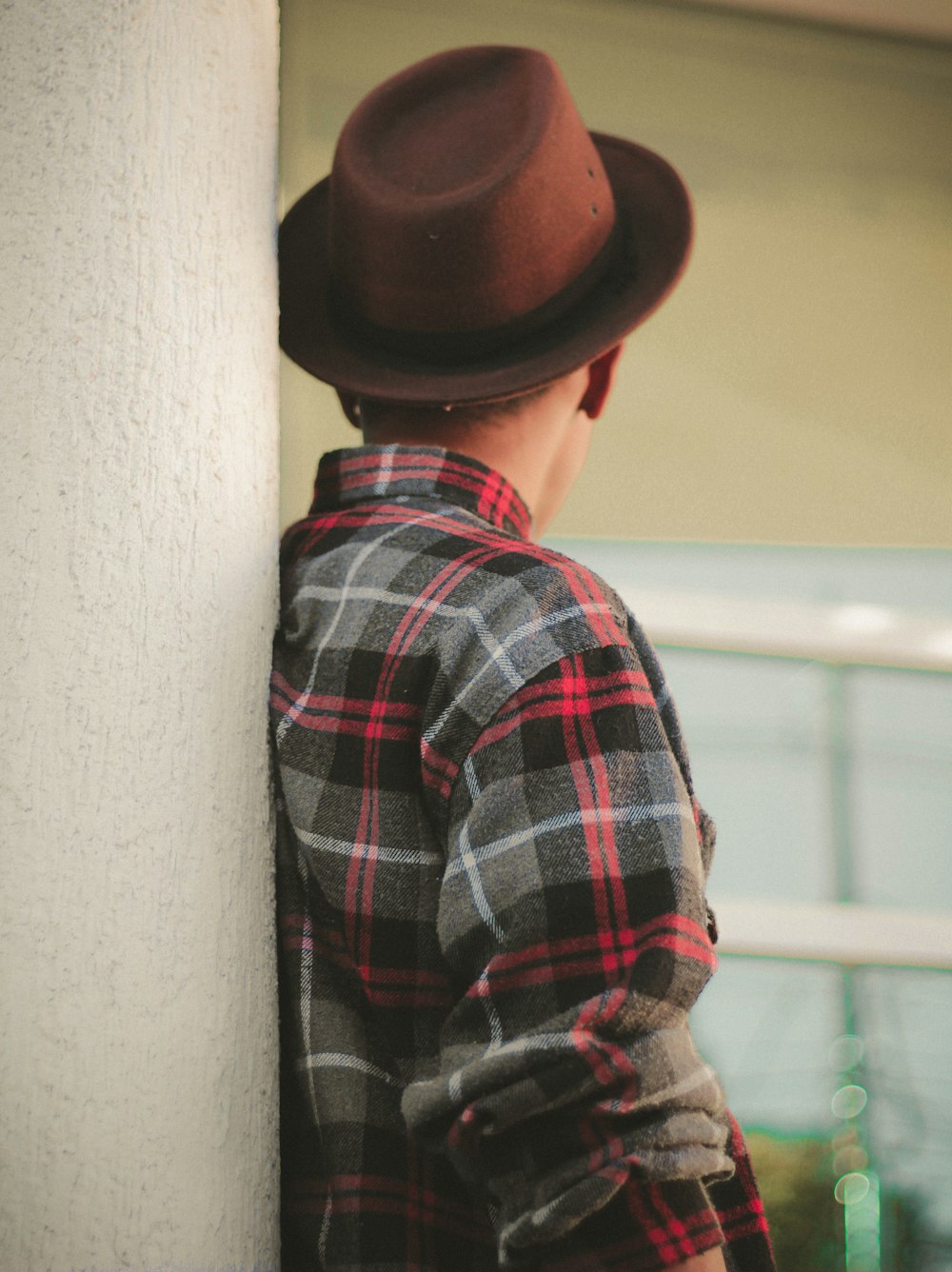 person wearing red, black, and white plaid shirt and brown hat