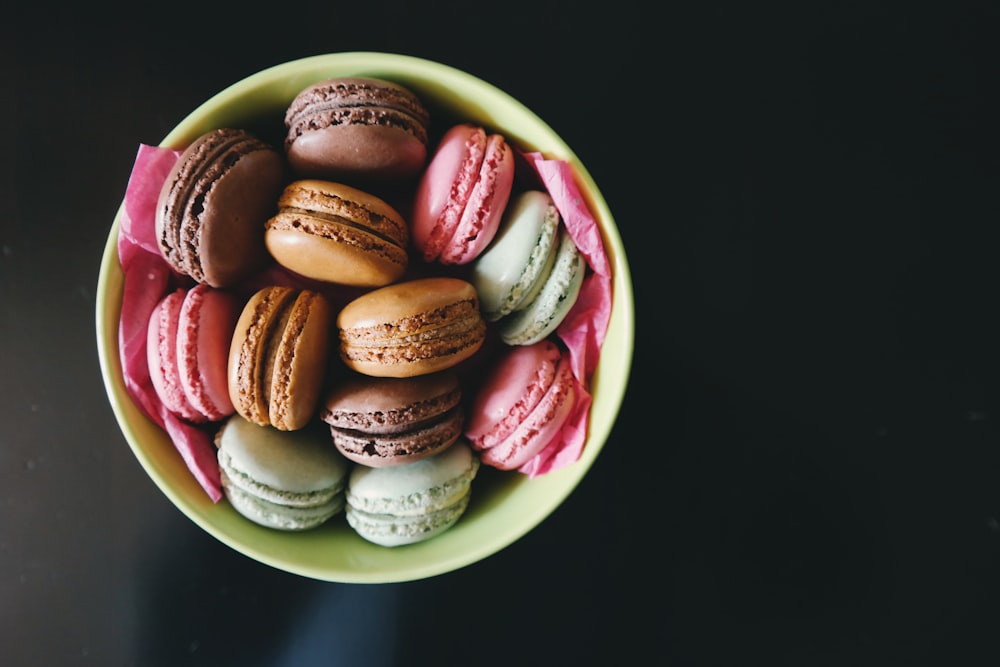 Colored cookies with frosting in the middle, sitting in a bowl.