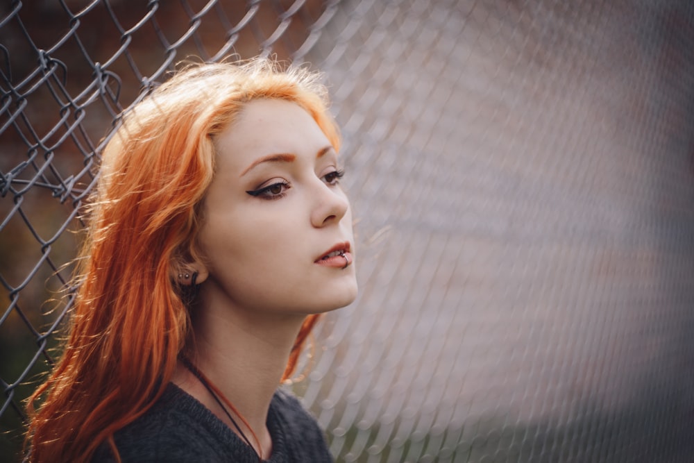 woman leaning on gray fence