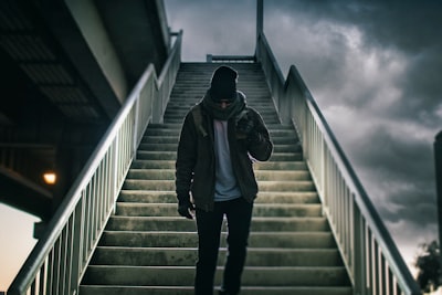 man wearing brown jacket walking on the stair under black sky division zoom background