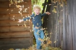 Children jumping into a pile of colorful autumn leaves in the front yard.