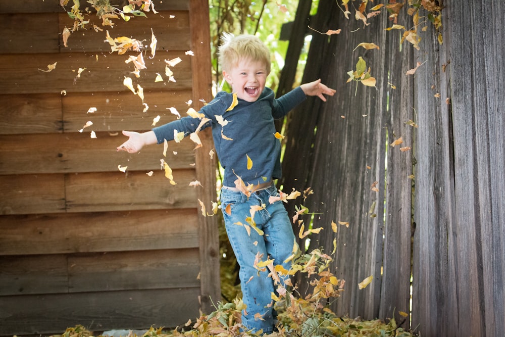 落ち葉のある柵の近くの男の子の写真