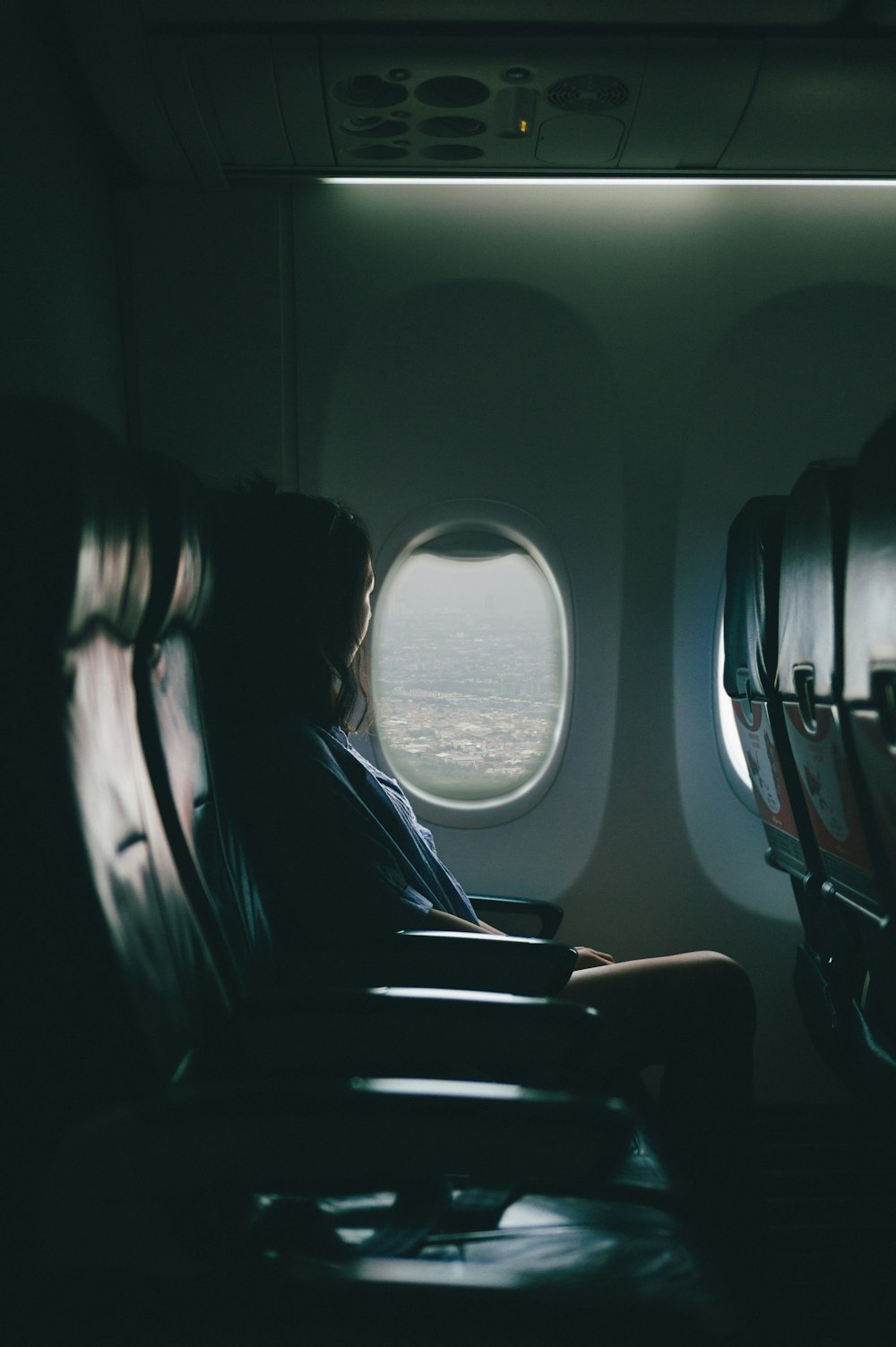 여자는 비행기 안쪽 창문 근처 좌석에 앉는다