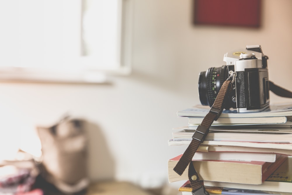 macchina fotografica nera della pellicola sopra i libri impilati all'interno della stanza ben illuminata