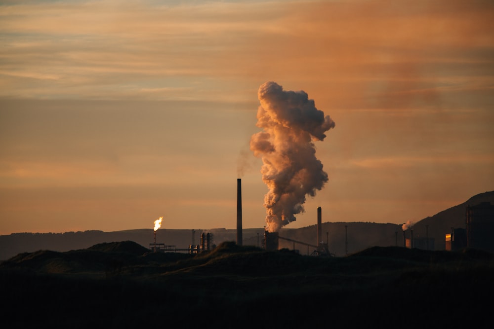 a smokestack emits from a factory at sunset