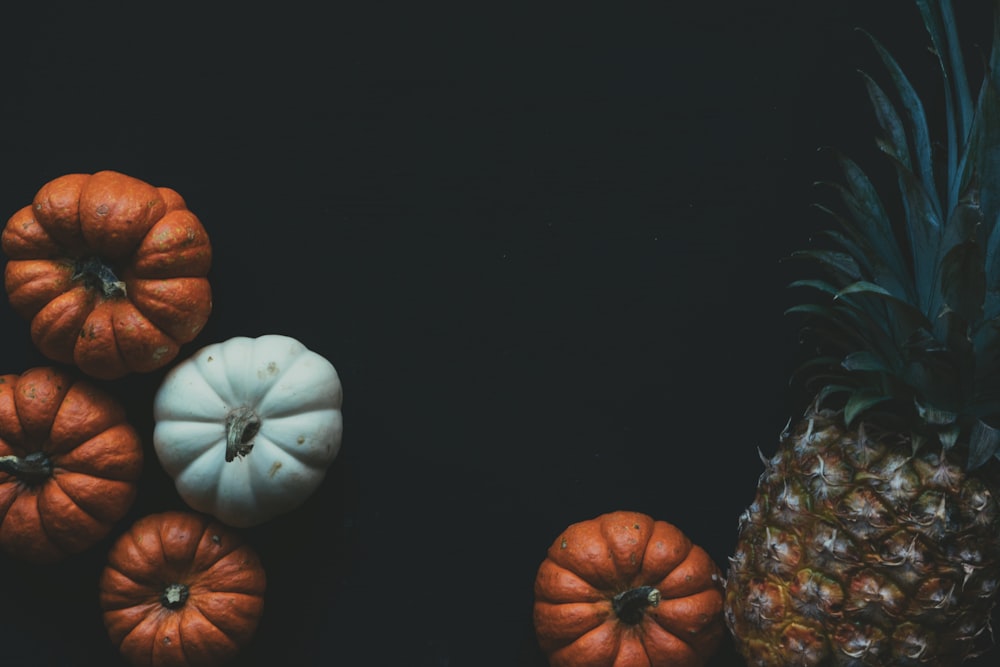 four orange and white pumpkin squashes and one pineapple