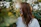 Photo of a relaxed woman outdoors, surrounded by soft greenery, radiating warmth and ease.
