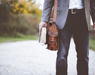 man holding book on road during daytime