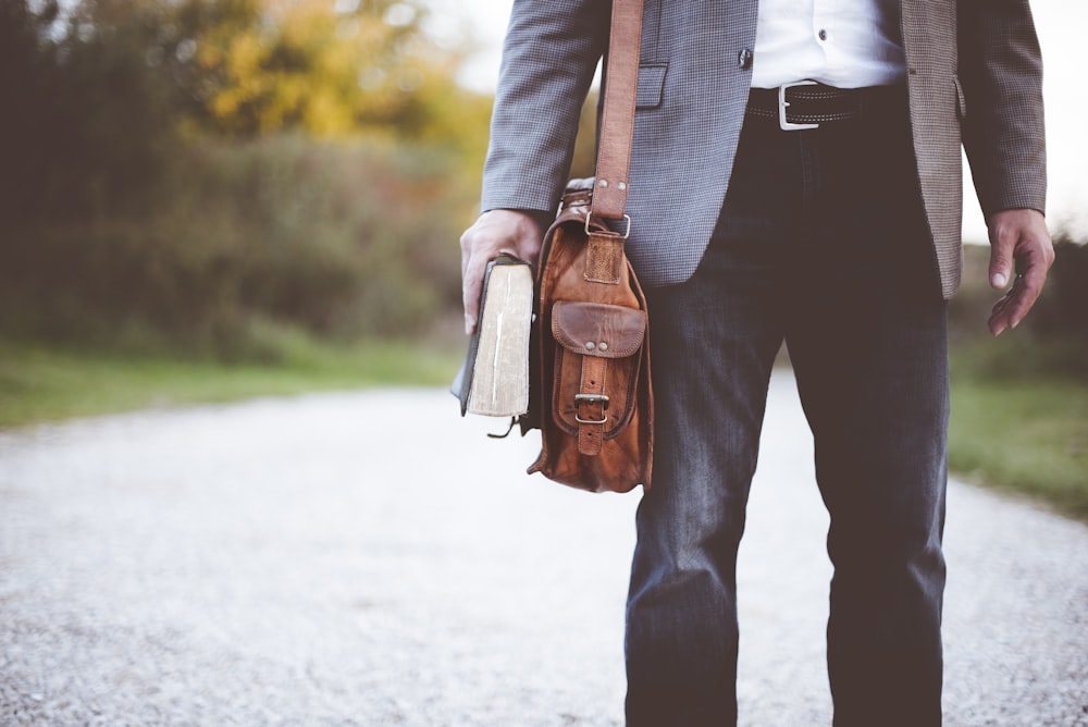 homme tenant un livre sur la route pendant la journée