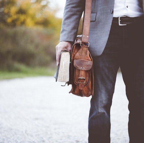 man holding book on road during daytime