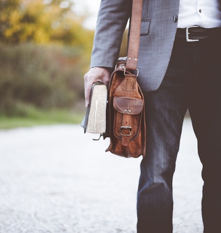 man holding book on road during daytime