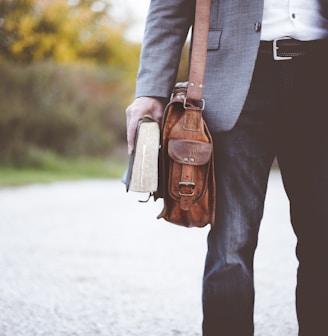 man holding book on road during daytime