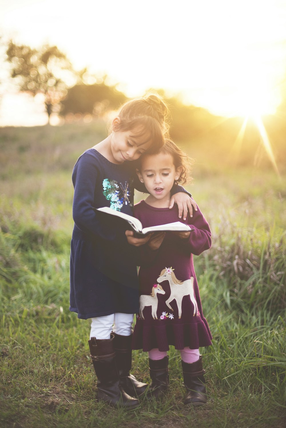 Mão esquerda da menina enrolar a criança enquanto lê livro durante a hora dourada