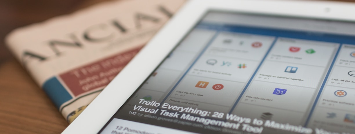 white tablet computer on top of newspaper