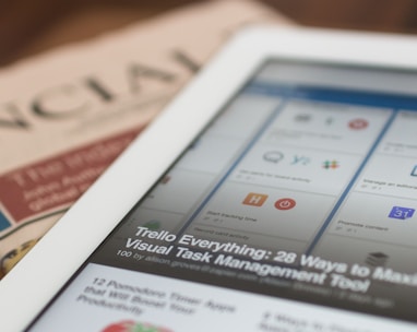 white tablet computer on top of newspaper