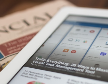 white tablet computer on top of newspaper