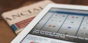 white tablet computer on top of newspaper