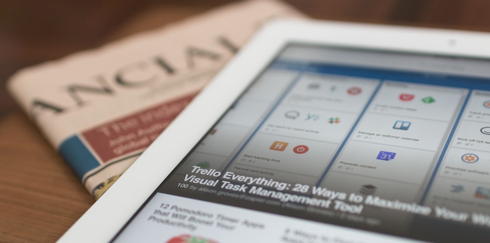 white tablet computer on top of newspaper