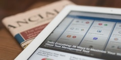 white tablet computer on top of newspaper