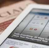 white tablet computer on top of newspaper