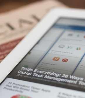 white tablet computer on top of newspaper