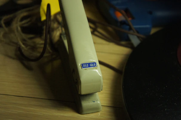 A close-up of a sleek yellow stapler resting on a wooden office desk with scattered documents.
