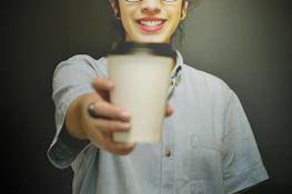 Friendly barista handing a coffee cup to a smiling customer at the truck window.