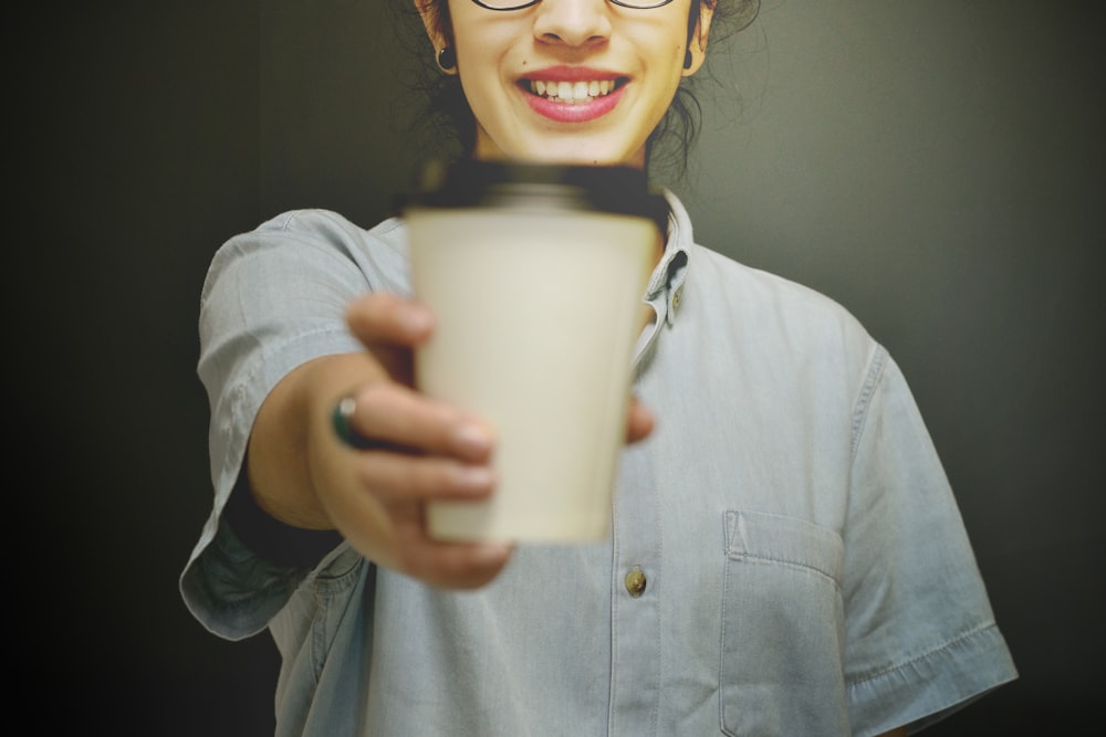 femme tenant une tasse de café blanche et noire