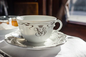 An elegant black ceramic cup with a delicate gold rim, resting on a matching saucer.