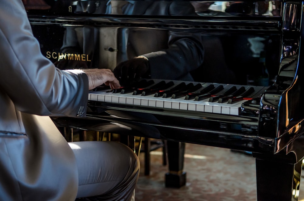 man sits on bench playing piano