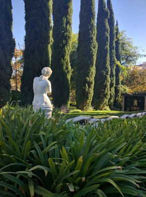 Outdoor marble sculpture emerging from lush landscaping under bright daylight