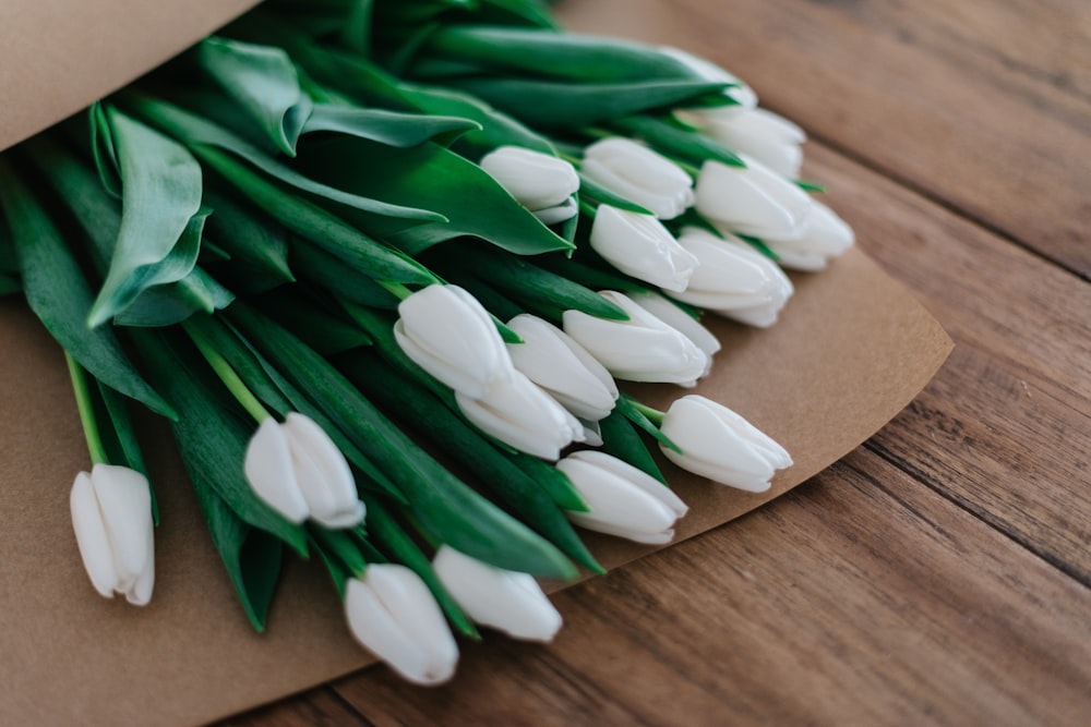 fotografia ravvicinata di bouquet di fiori dai petali bianchi su un tavolo di legno marrone