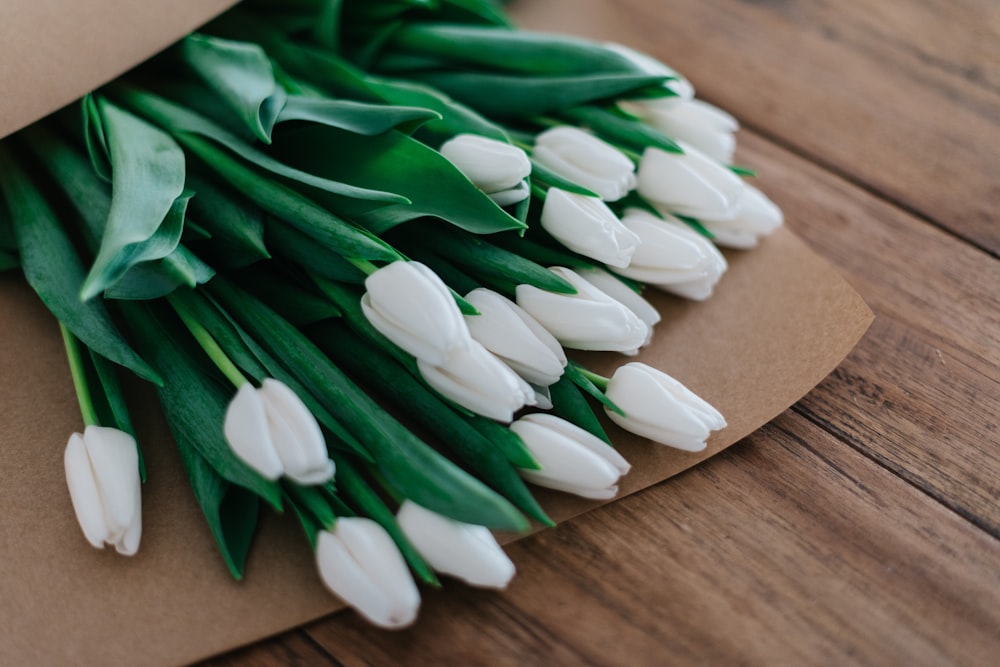 Nahaufnahme eines weißblättrigen Blumenstraußes auf einem braunen Holztisch